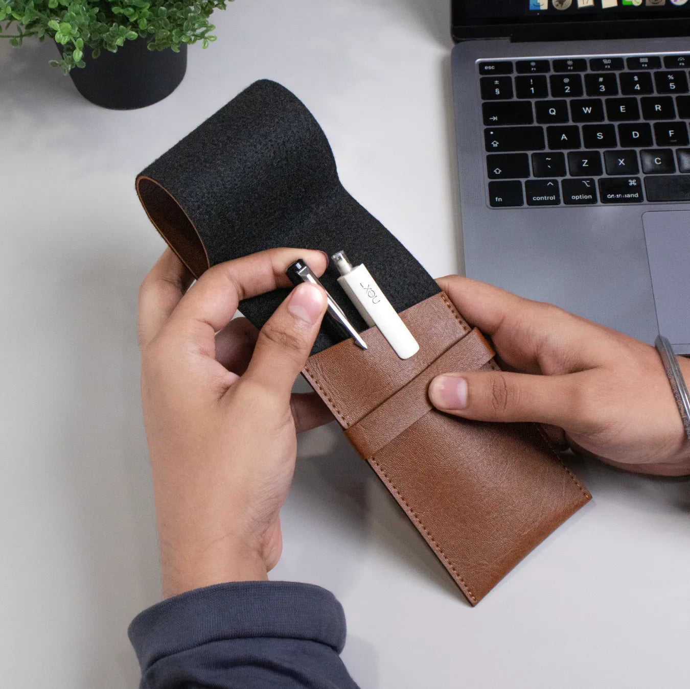 Hand holding brown leather pen pouch with stylus