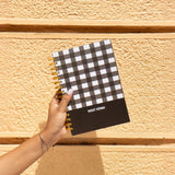 Hand holding checkmate notebook with name 'Rohit Verma'