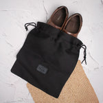 Black drawstring shoe bag with shoes inside